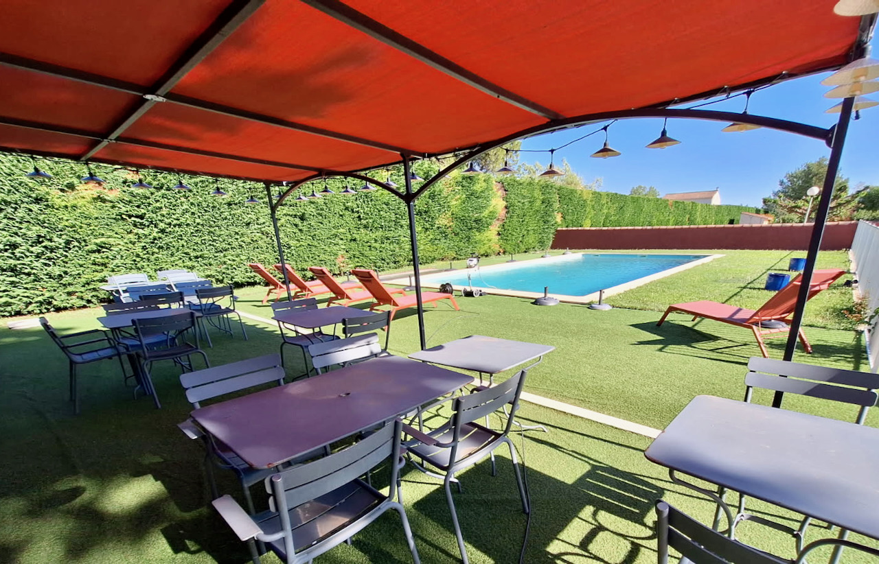 Terrasse ombragée avec tables au bord de la grande piscine 12 × 6 m de l'Hôtel La Perna